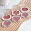 Heart-shaped blush compact with pink blush on a wooden surface