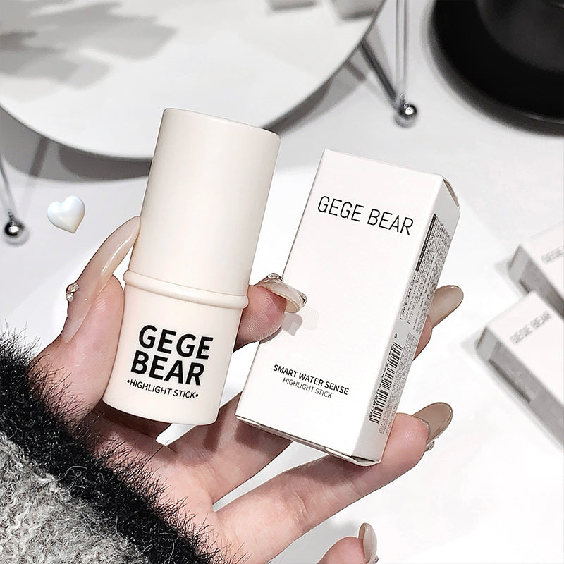 Hand holding a 'GEGE BEAR' highlight stick with its packaging on a white surface.