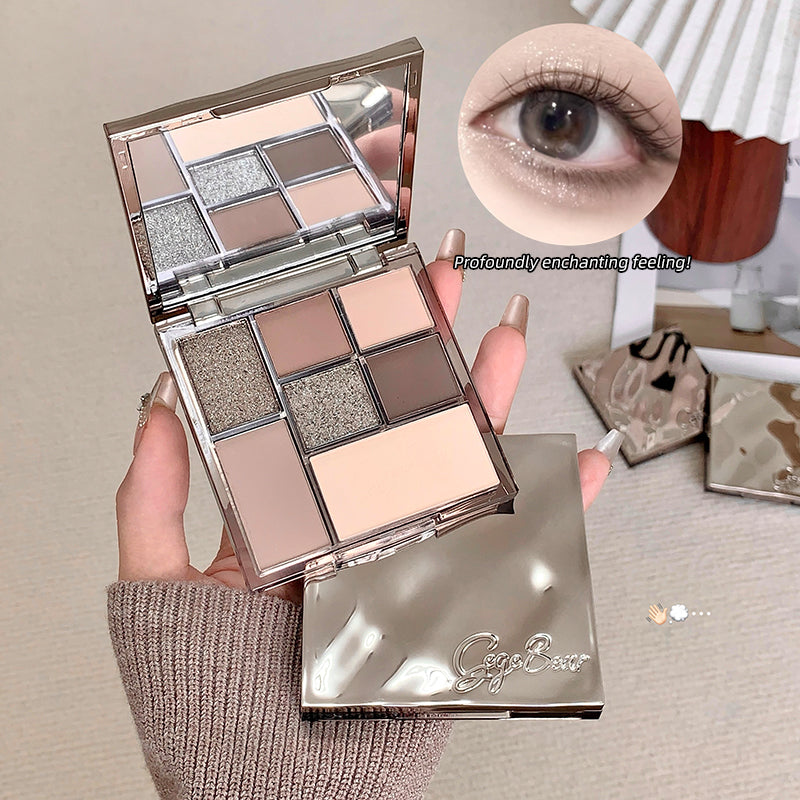 Makeup palette with eyeshadow shades held by a hand, close-up of eye wearing the makeup.