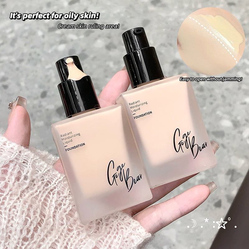Two bottles of 'Go Be' foundation held by a hand on a textured surface.