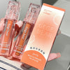 Two lip glosses and their packaging held by a hand on a neutral background