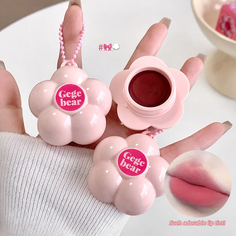 Pink lip balm with 'Gege bear' branding held by a hand, showing close-up of lip balm and inset of lips.