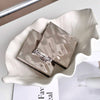 Silver book-shaped object on a white dish with a blurred background