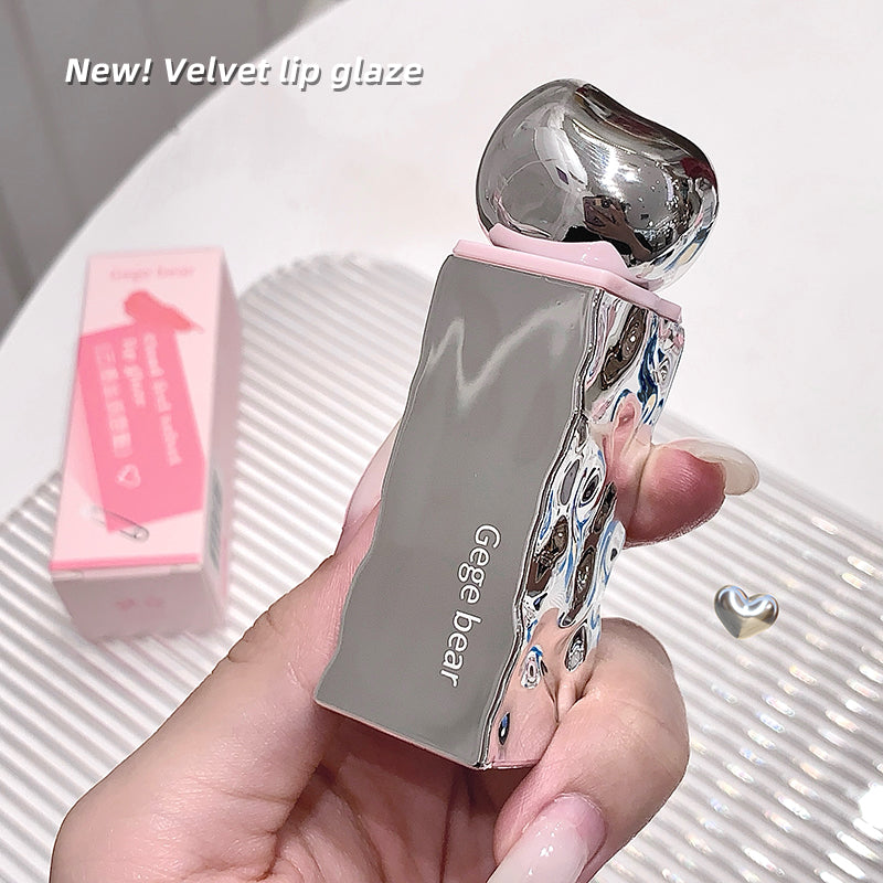 Silver lip gloss with pink packaging held by a hand on a white background