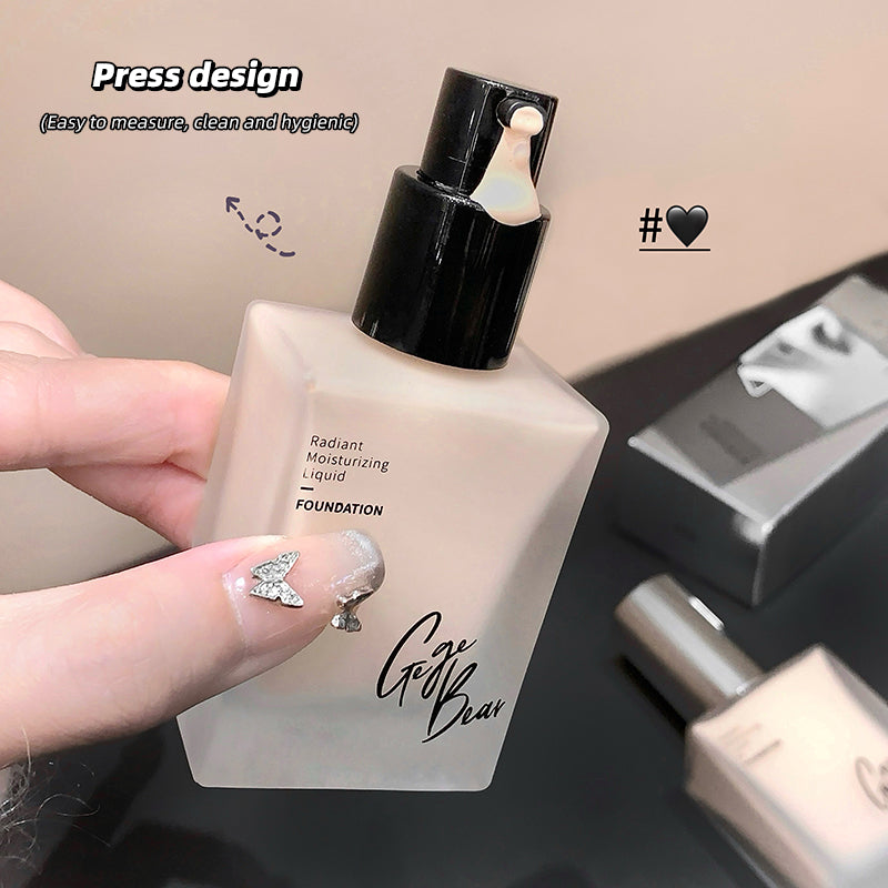 Foundation bottle held by a hand with decorative nails, on a neutral background.