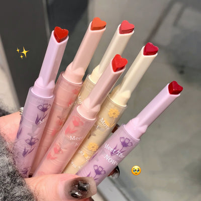 Set of lip glosses with heart-shaped caps held by a person.