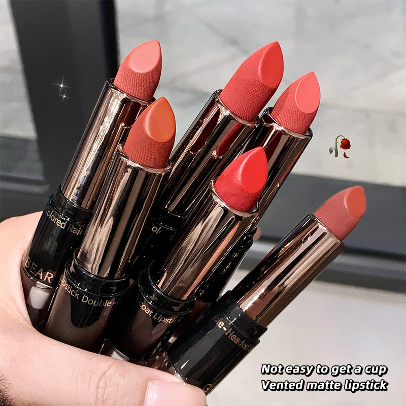 Five lipsticks of different shades held by a hand with a blurred background