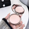 Hand holding a compact powder with a blurred background