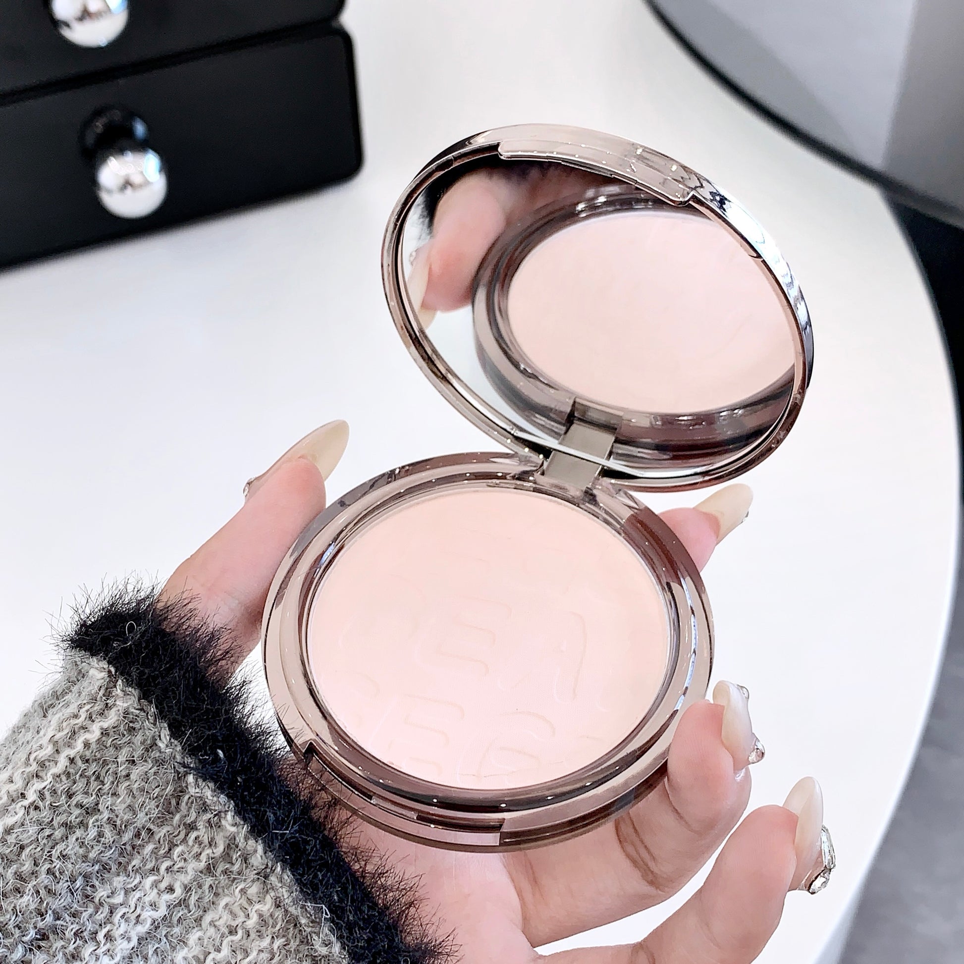 Hand holding a compact powder with a blurred background