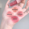 Hand holding four different shades of lipstick on a gray background