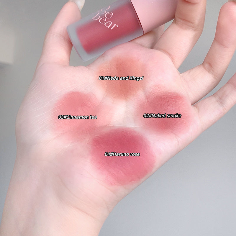 Hand holding four different shades of lipstick on a gray background