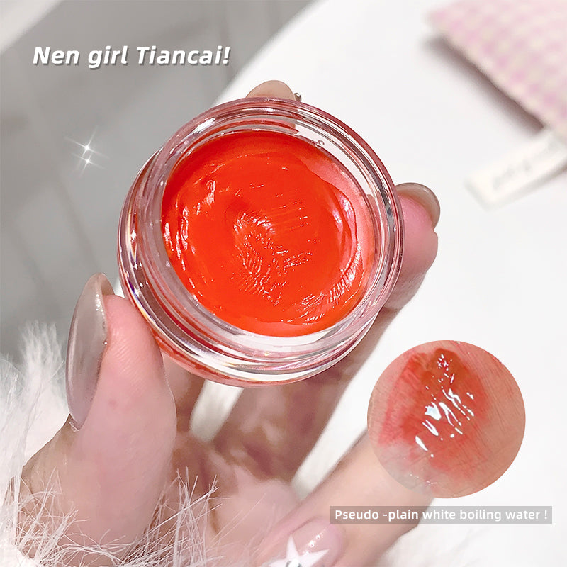 Hand holding a small jar of bright orange cream with a blurred background