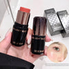 Two black cosmetic sticks with 'GEGE BEAR' branding held by a hand, with a close-up of a person's eye and makeup inset.