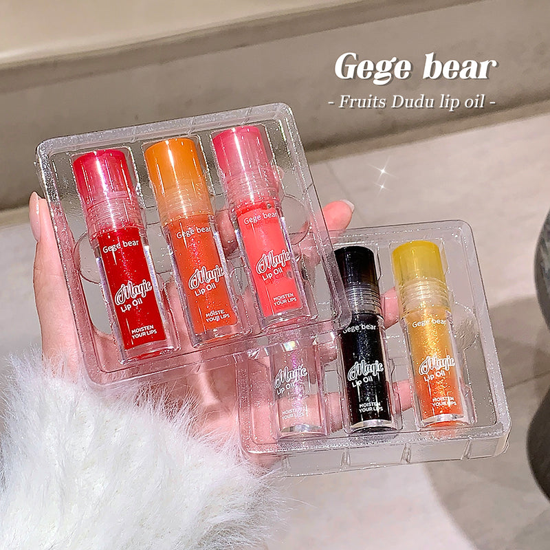 Set of lip oils in clear packaging held by a hand, with 'Gege bear' branding.