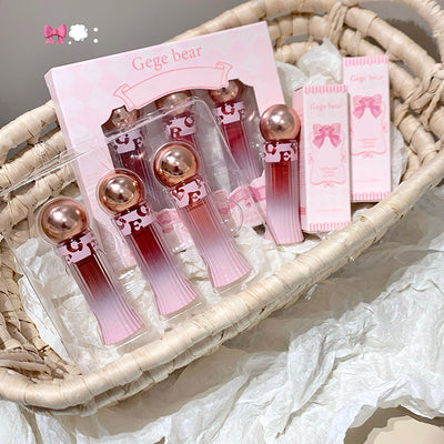 Set of pink lip glosses with rose gold accents in a wicker basket