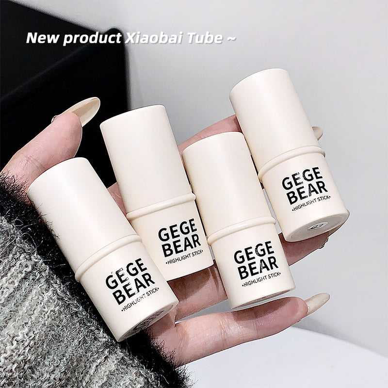 Hand holding four 'GEGE BEAR' highlight stick tubes with a blurred background