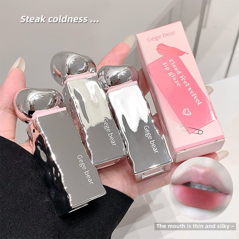 Silver lip glosses with pink packaging held by a hand, close-up of lips with gloss applied.