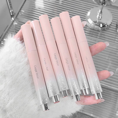 Set of gradient pink lip glosses held by a hand on a reflective surface.