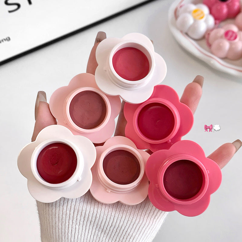 Flower-shaped lip balm containers with pink and red shades on a white surface.