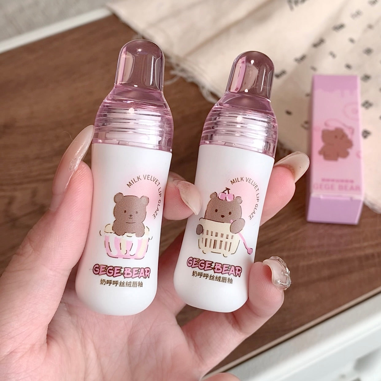 Two small bottles with bear-themed labels held in a hand on a wooden surface.