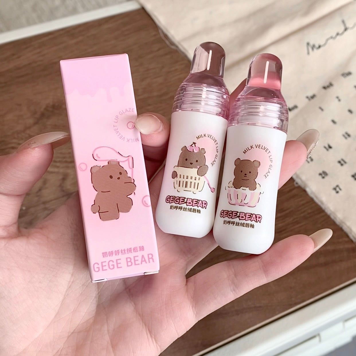 Two small bottles and a pink box with 'GEGE BEAR' branding held in a hand.