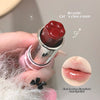 Pink lipstick with a paw design on the cap, held by a hand, with a close-up of lips wearing the lipstick.