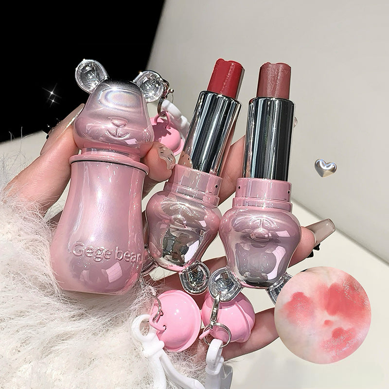 Set of pink and silver makeup products including lipsticks and a bottle with bear-like design.
