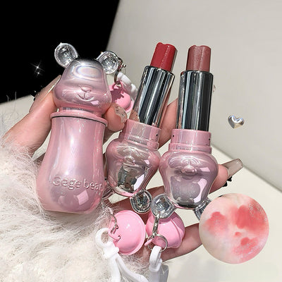 Set of pink and silver makeup products including lipsticks and a bottle with bear-like design.