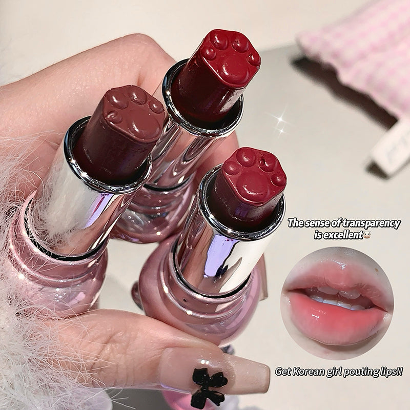 Three lipsticks with paw-shaped caps held by a hand, with an inset showing lips wearing the lipstick.