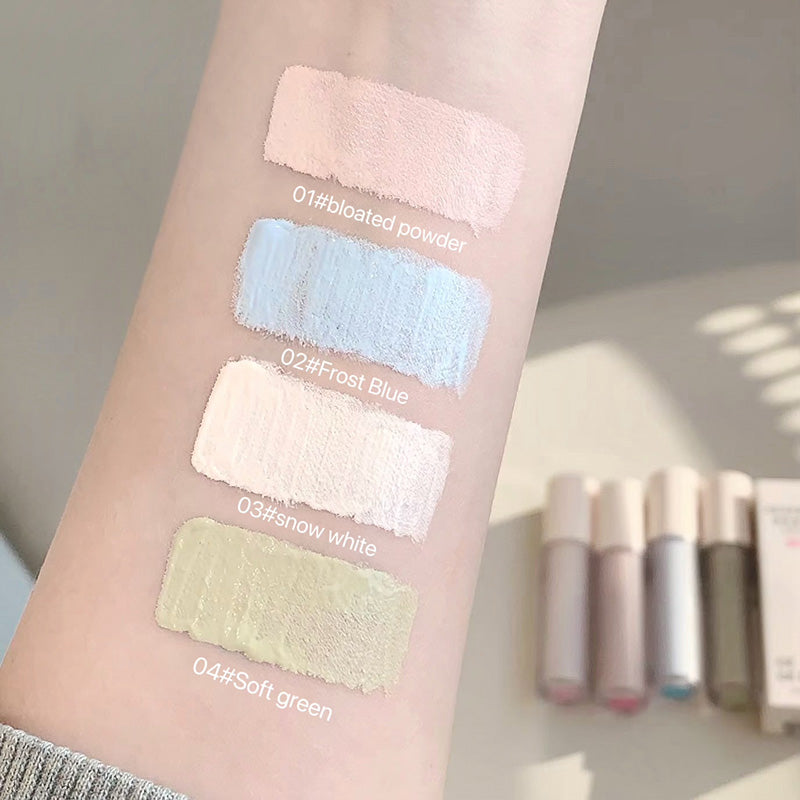 Color swatches on a person's arm with labeled makeup colors and bottles in the background.
