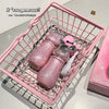 Pink lip gloss set in a pink metal basket on a light gray surface.