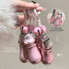 Pink bottle-shaped keychain with a flamingo charm held by a hand against a neutral background.