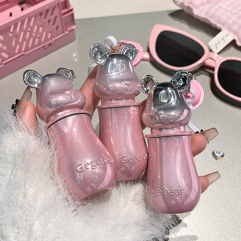 Three pink bear-shaped bottles held by a hand, with sunglasses in the background.
