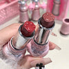 Two lipsticks with paw print caps held by a hand against a pink background.