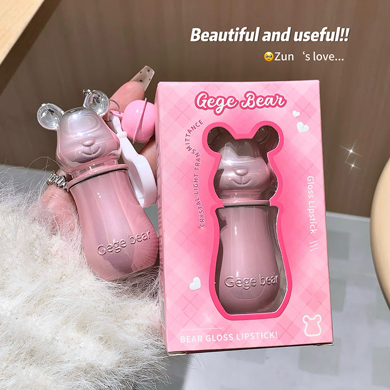 Pink bear-shaped gloss lipstick with packaging on a soft surface