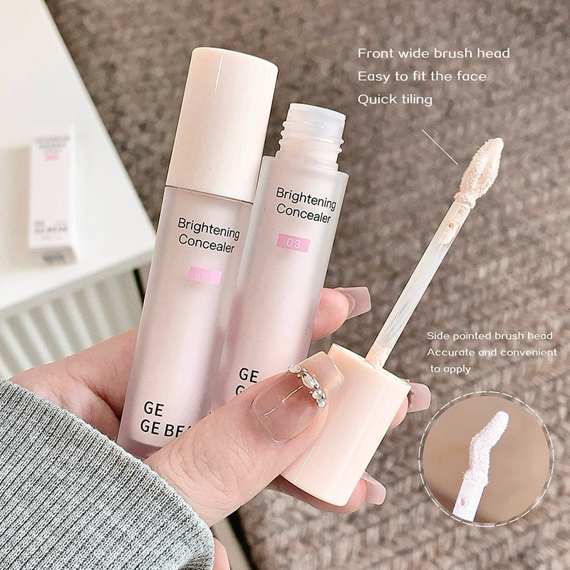 Two bottles of 'Brightening Concealer' with a brush applicator held by a hand on a neutral background.
