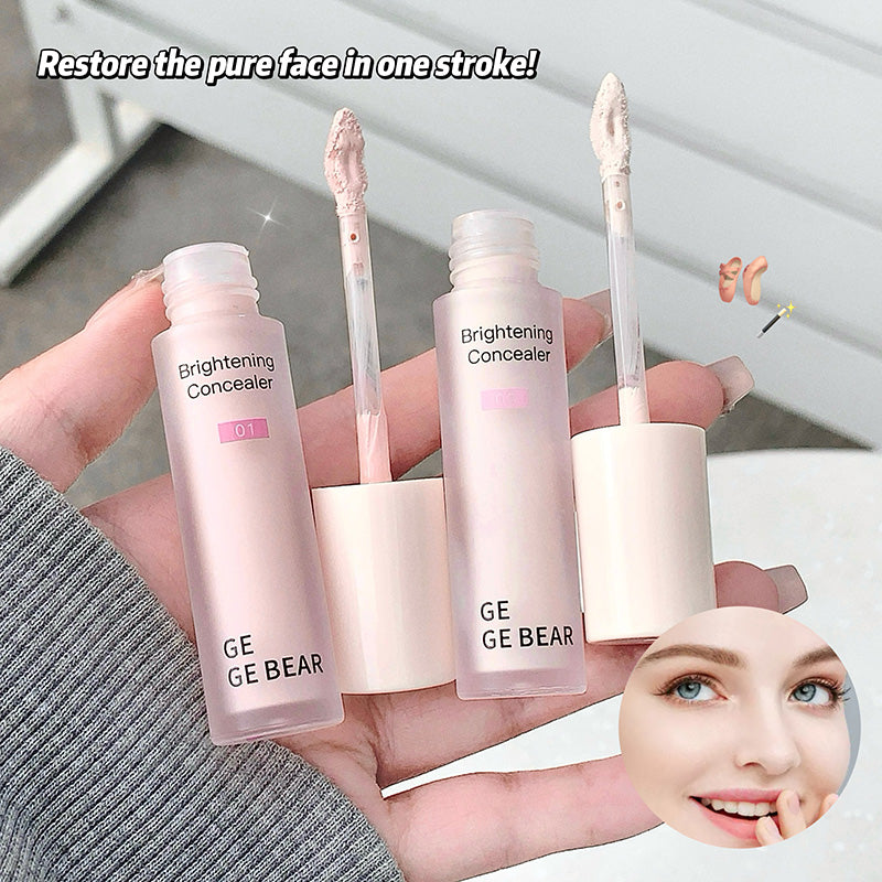 Hand holding two GE GE BEAR brightening concealers with a blurred background