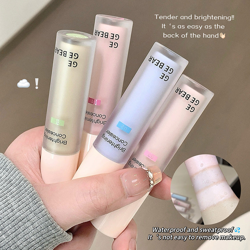 Hand holding four GE BEAR concealer tubes with text on a neutral background