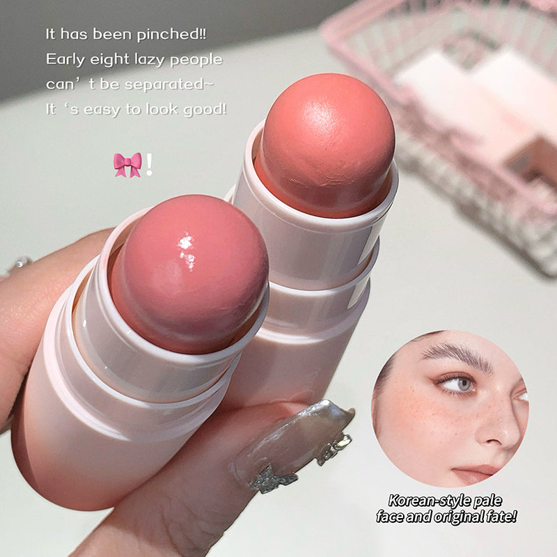 Two pink lip balms held by a hand with a blurred background