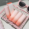 Set of pink and orange gradient bottles with a box labeled 'Geege Beauty' in a pink basket.