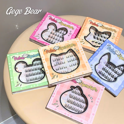 Set of false eyelashes in colorful boxes on a round surface with 'Gegge Bear' branding.
