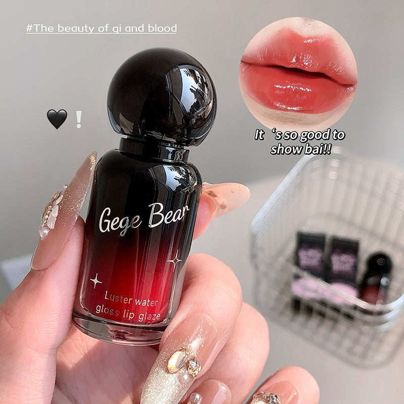 Gege Bear lip gloss bottle held by a hand with a close-up of glossy lips.