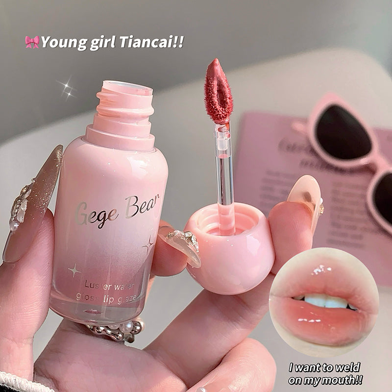 Pink lip gloss with applicator held by a hand, close-up of product and lips shown.
