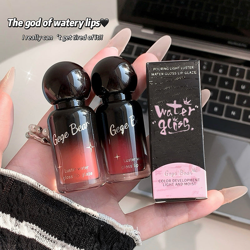 Two bottles and a box of Gege Bear lip gloss held in front of a laptop.