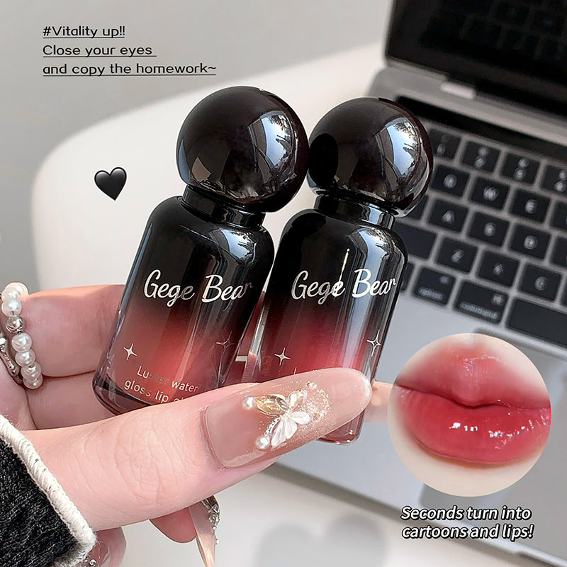 Two black bottles of 'Gege Bear' lip gloss held by a hand with a laptop in the background.