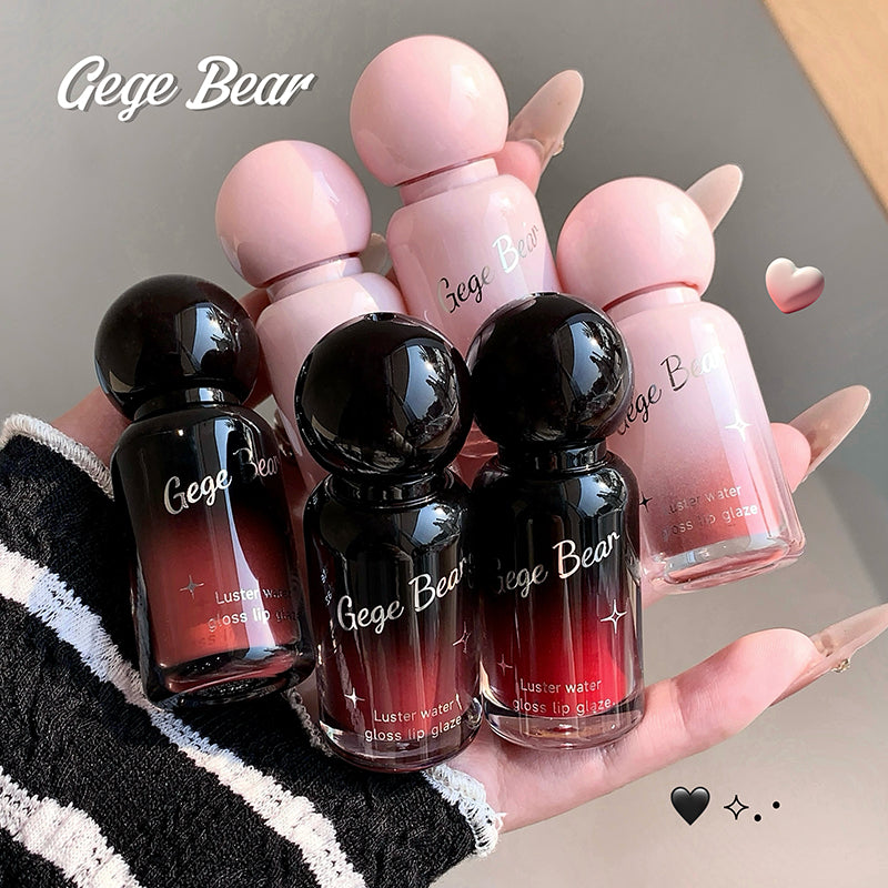 Set of Gege Bear lip gloss bottles held in a hand with a neutral background