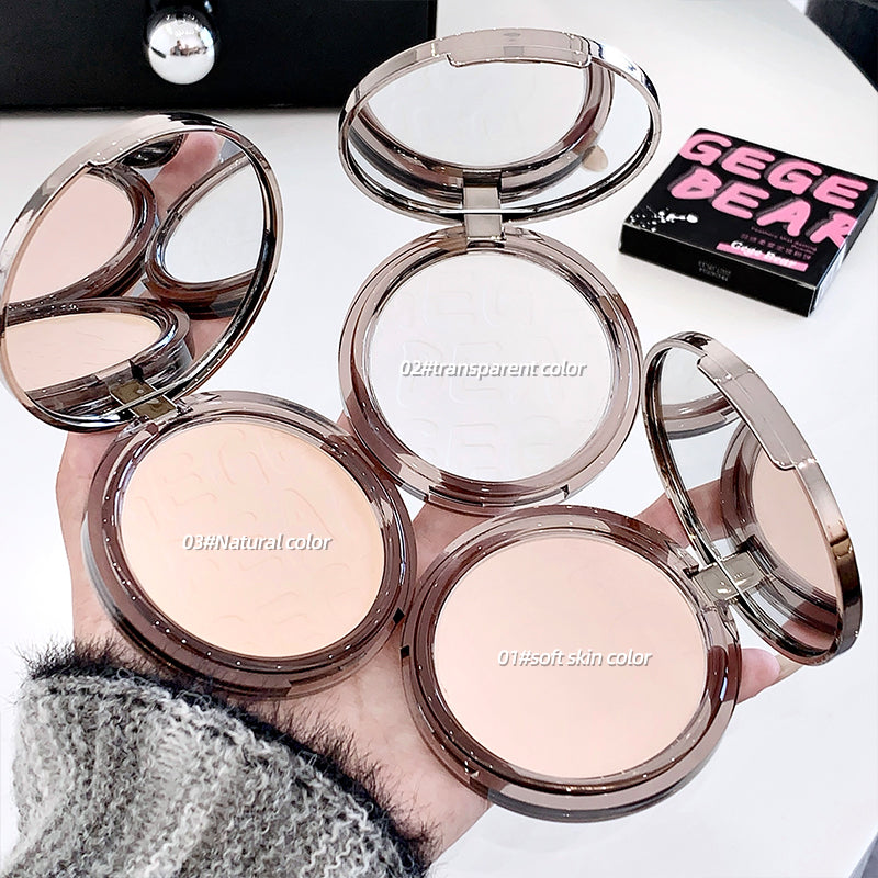 Compact powder cases with open lids showing different shades held by a hand.