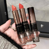 Three lipsticks held in a hand with a blurred background