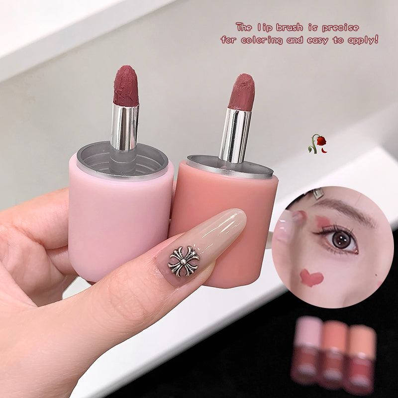 Pink lip brush with silver ferrule held by a hand, close-up view.