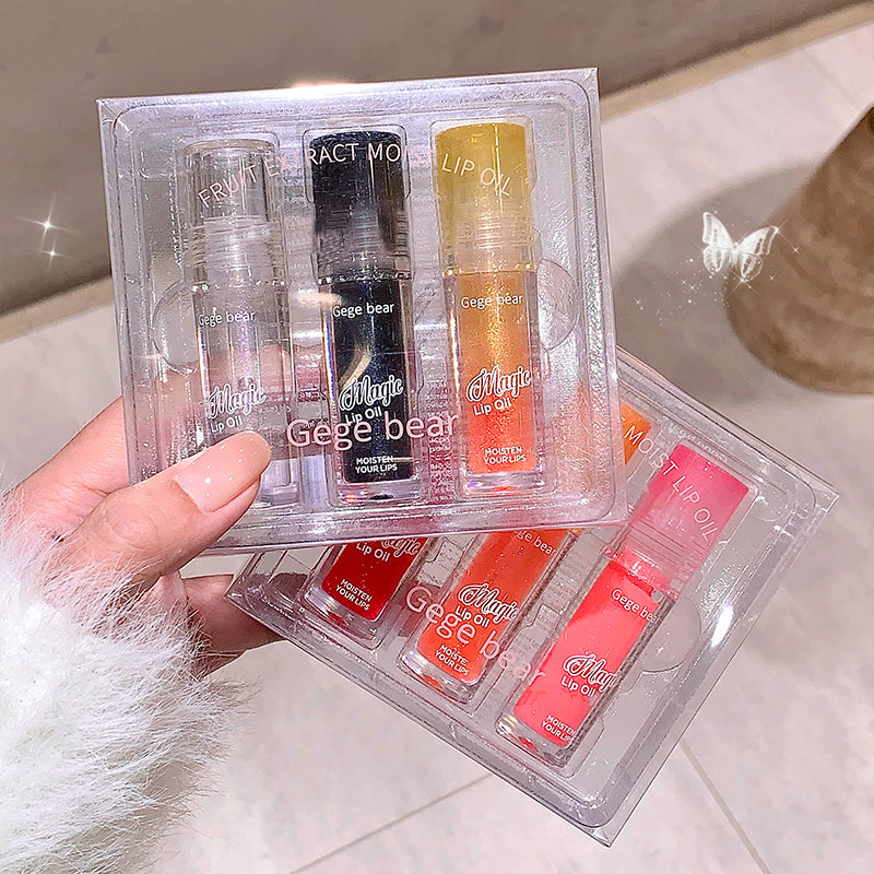 Set of lip glosses in clear packaging held by a hand on a light background